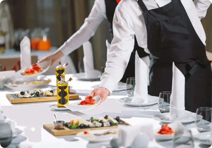 Waiters serving dishes at a restaurant table