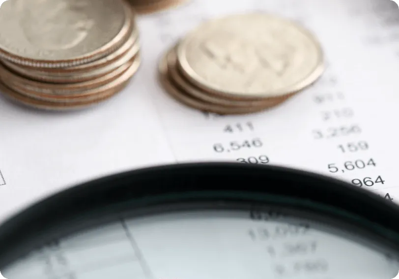 Coins and financial figures seen through a magnifying glass